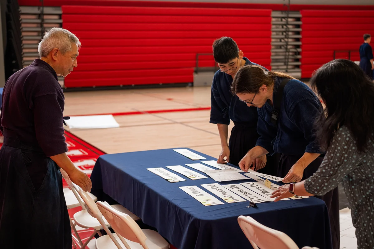 Kenshi and volunteers organizing name strips at a setup table