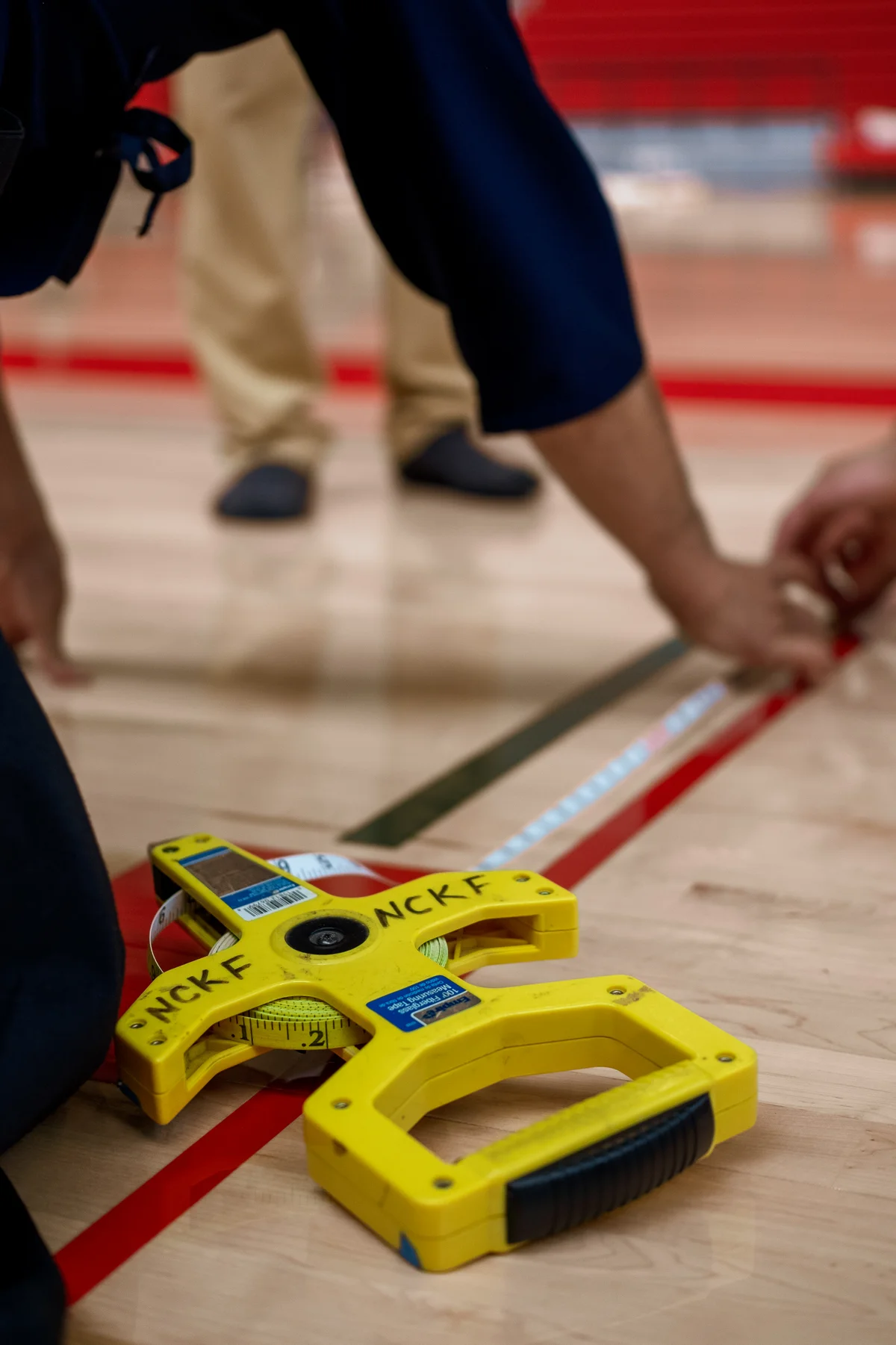Volunteers measuring and taping a court on the gym floor